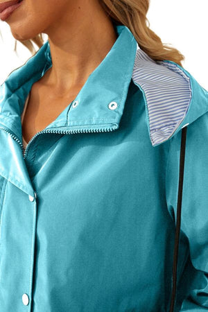 Close-up of a teal water resistant windbreaker jacket with striped hood lining and snap buttons
