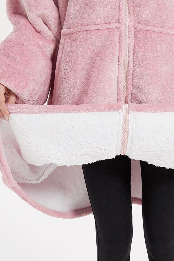 Close-up of oversized ultra soft hooded blanket in pink with white sherpa lining and front zipper detail