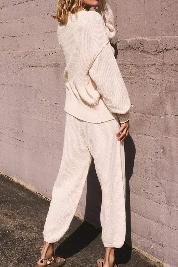 Woman wearing cream-colored two-piece knitwear relaxed co-ord set standing against a textured wall