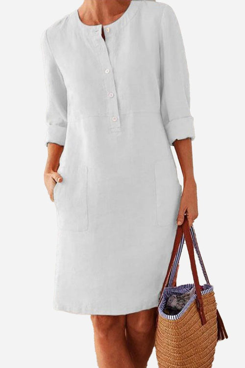 White lightweight cotton dress with 3/4 rolled sleeves and front buttons, featuring pockets and a casual knee-length fit.