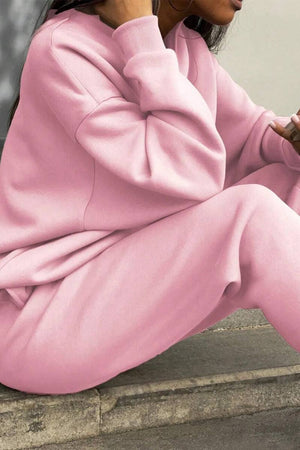 Woman wearing pink cotton-blended two-piece tracksuit sitting outdoors