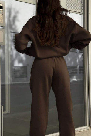 Woman wearing a brown cotton-blended two-piece tracksuit standing with hands on hips, back view.