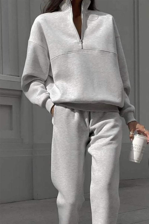 Light gray cotton-blended two-piece tracksuit with high collar and deep zipper, modeled outdoors holding a coffee cup.