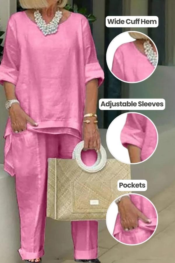 Pink asymmetrical two-piece trouser set with wide cuff hem, adjustable sleeves, and pockets, styled with a necklace and handbag
