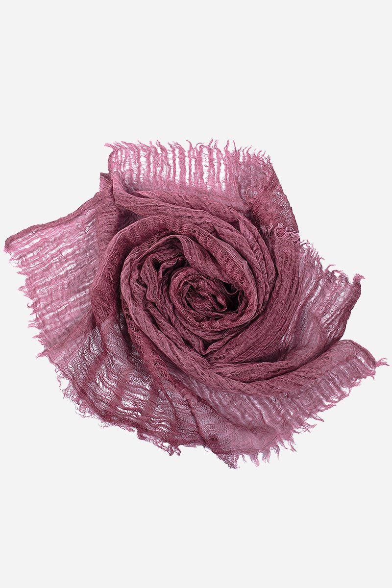 Lightweight linen scarf in dusty rose with frayed edges, folded in a rose shape