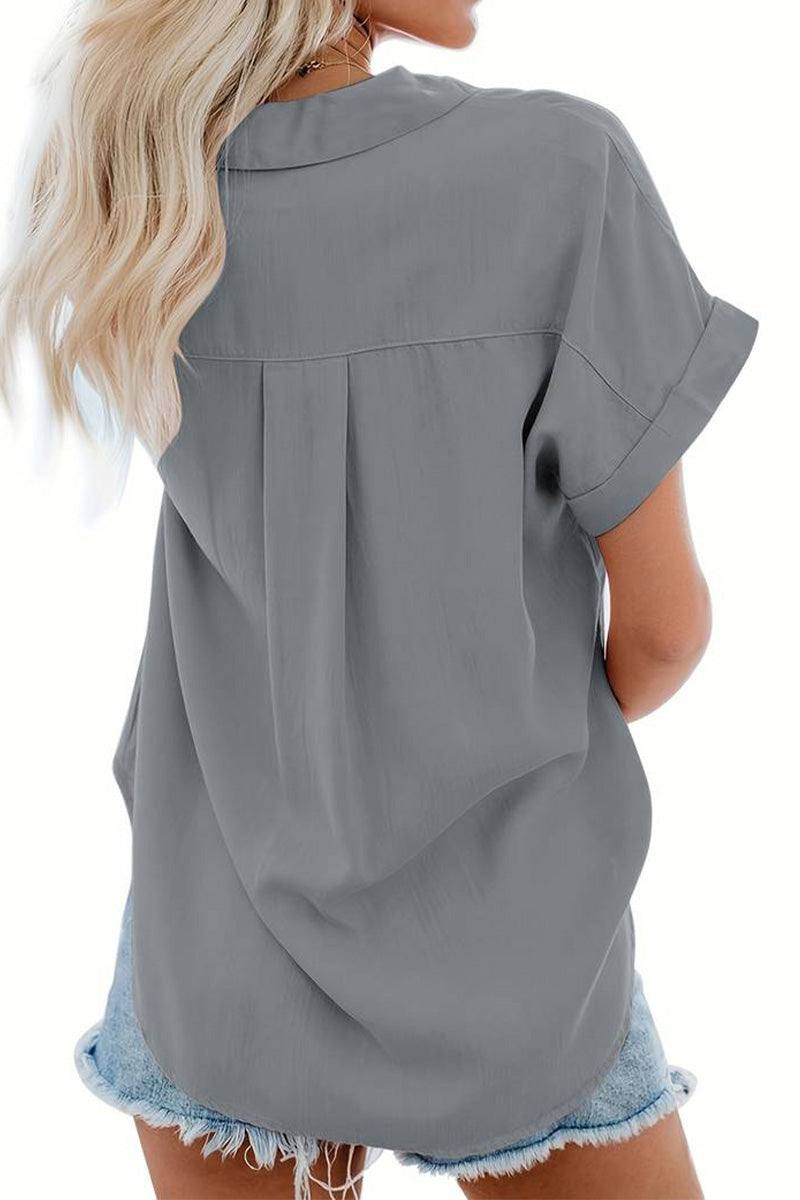 Back view of woman wearing grey V-Neck Collared Button Blouse with rolled short sleeves and denim shorts