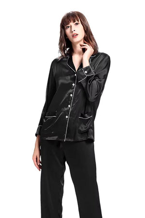 Woman wearing black long sleeve silk pajamas with button-up top and matching pants