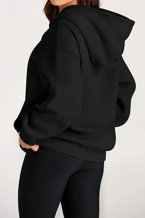 Woman wearing a black oversized fleece-lined hoodie with a relaxed fit and hood.