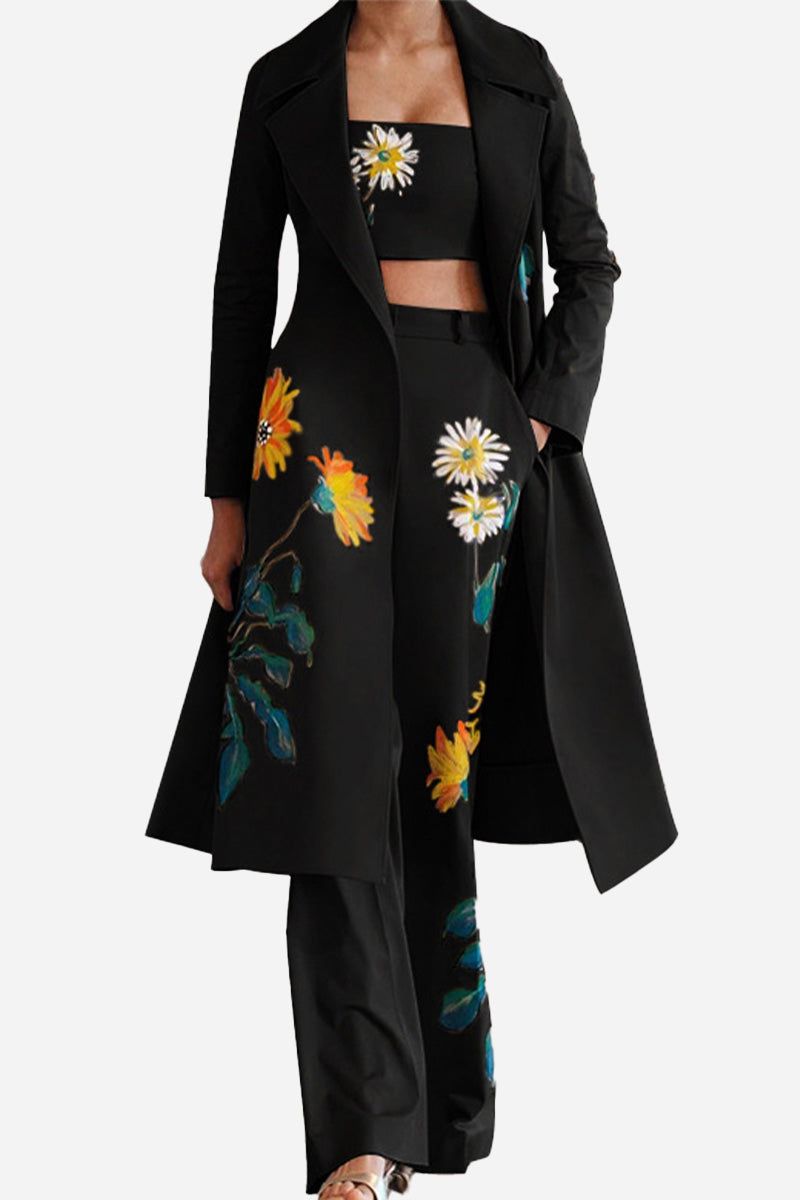 Woman wearing elegant black three-piece floral set with strapless top, long coat, and wide-leg pants featuring bright yellow and white flower prints