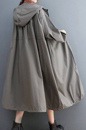 Oversized all-weather water-resistant windbreaker with hood, in neutral gray, worn over casual outfit.