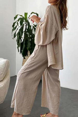 Woman wearing beige relaxed fit Vacation Essentials Cotton Set with wide-leg pants and oversized button-up top in casual indoor setting