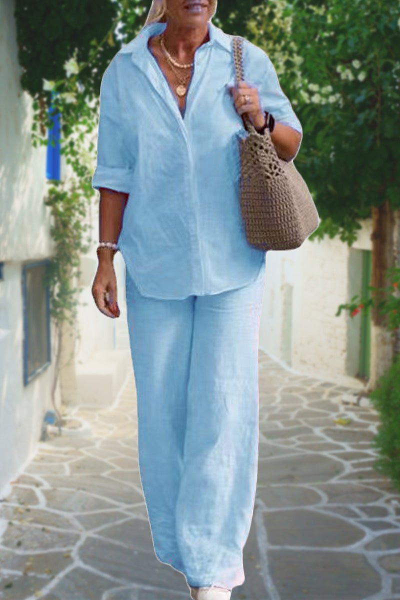 Woman wearing light blue linen shirt and pants casual chic duo outfit walking outdoors with woven handbag