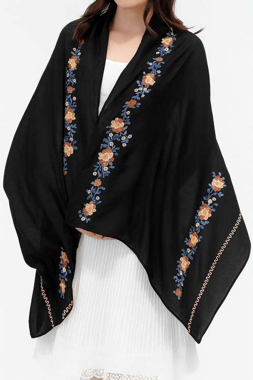 Black embroidered travel-must shawl wrap with floral design worn over white dress