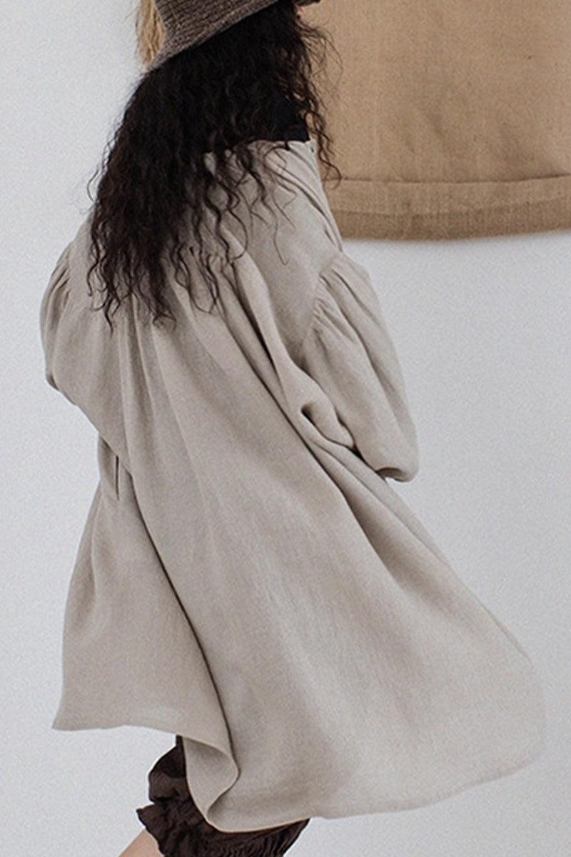 Woman wearing oversized 100% linen button-down tunic in neutral grey with flowy sleeves and relaxed fit