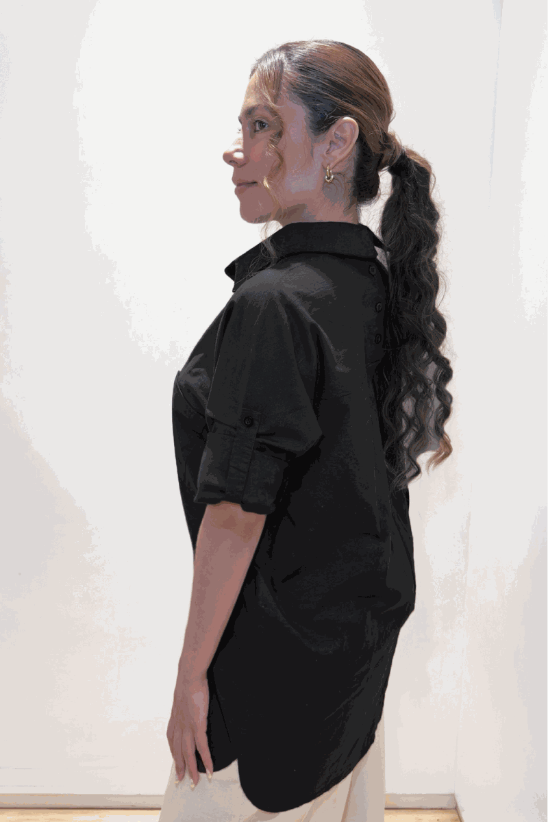 Woman wearing black oversized linen-leaved-in set shirt with rolled sleeves, side view