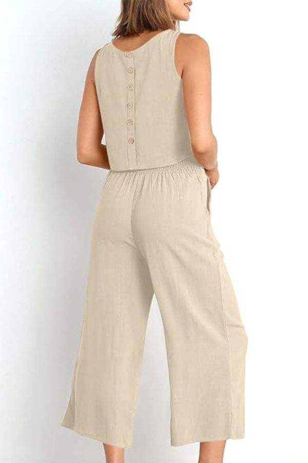 Woman wearing beige sleeveless Villa Lounge Linen Set with button-back cropped top and wide-leg pants with elastic waistband and side pockets.