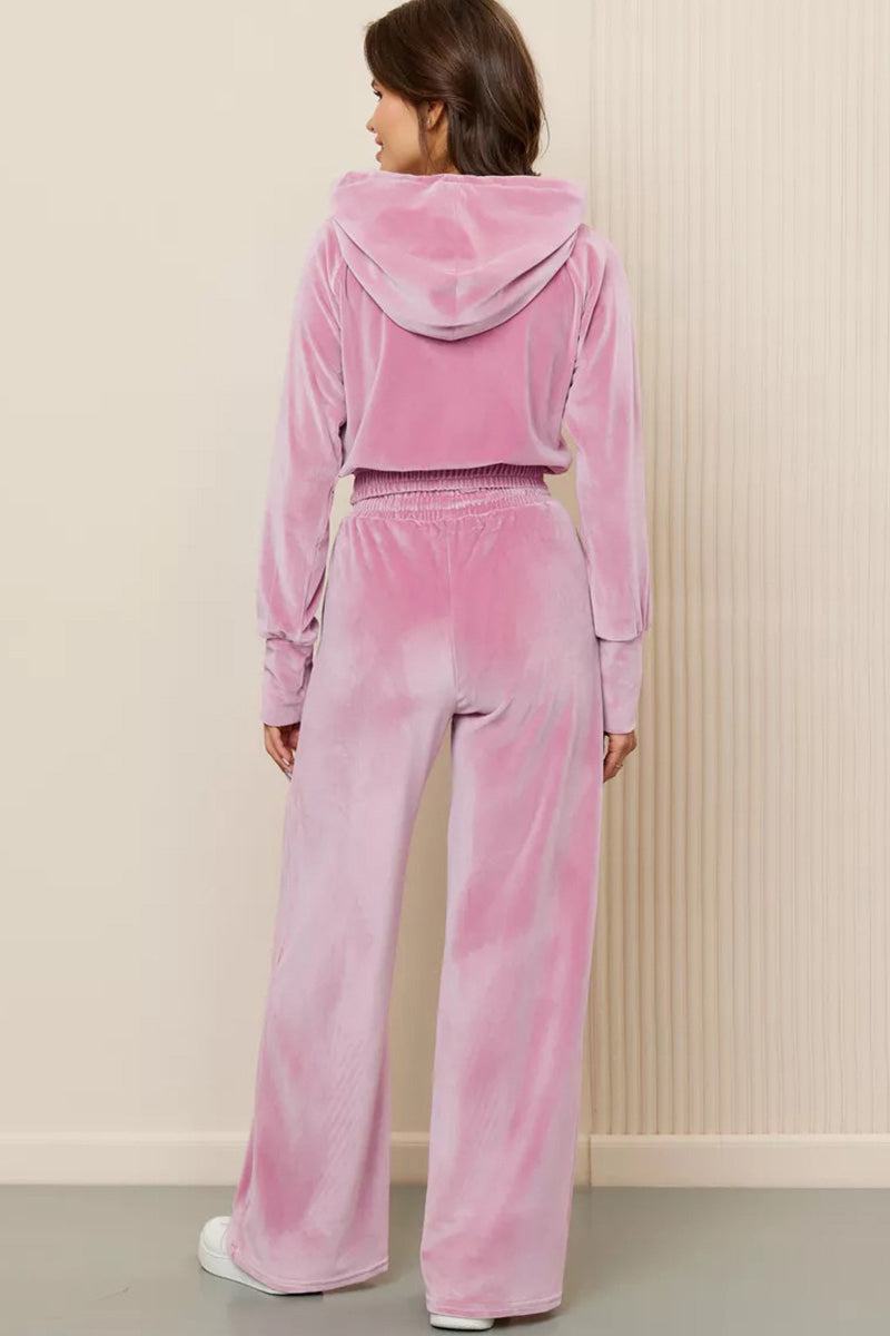 Woman wearing pink velour tracksuit with cropped hoodie and high-waist pants from the back