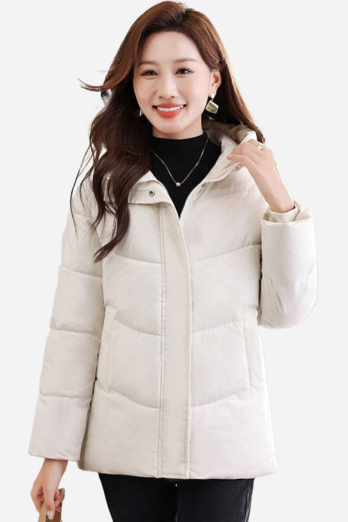 Woman wearing a mid-length, cream-colored Everyday Warmth Coat with hood, featuring lightweight 5-layer thermal insulation and a relaxed, flattering fit.