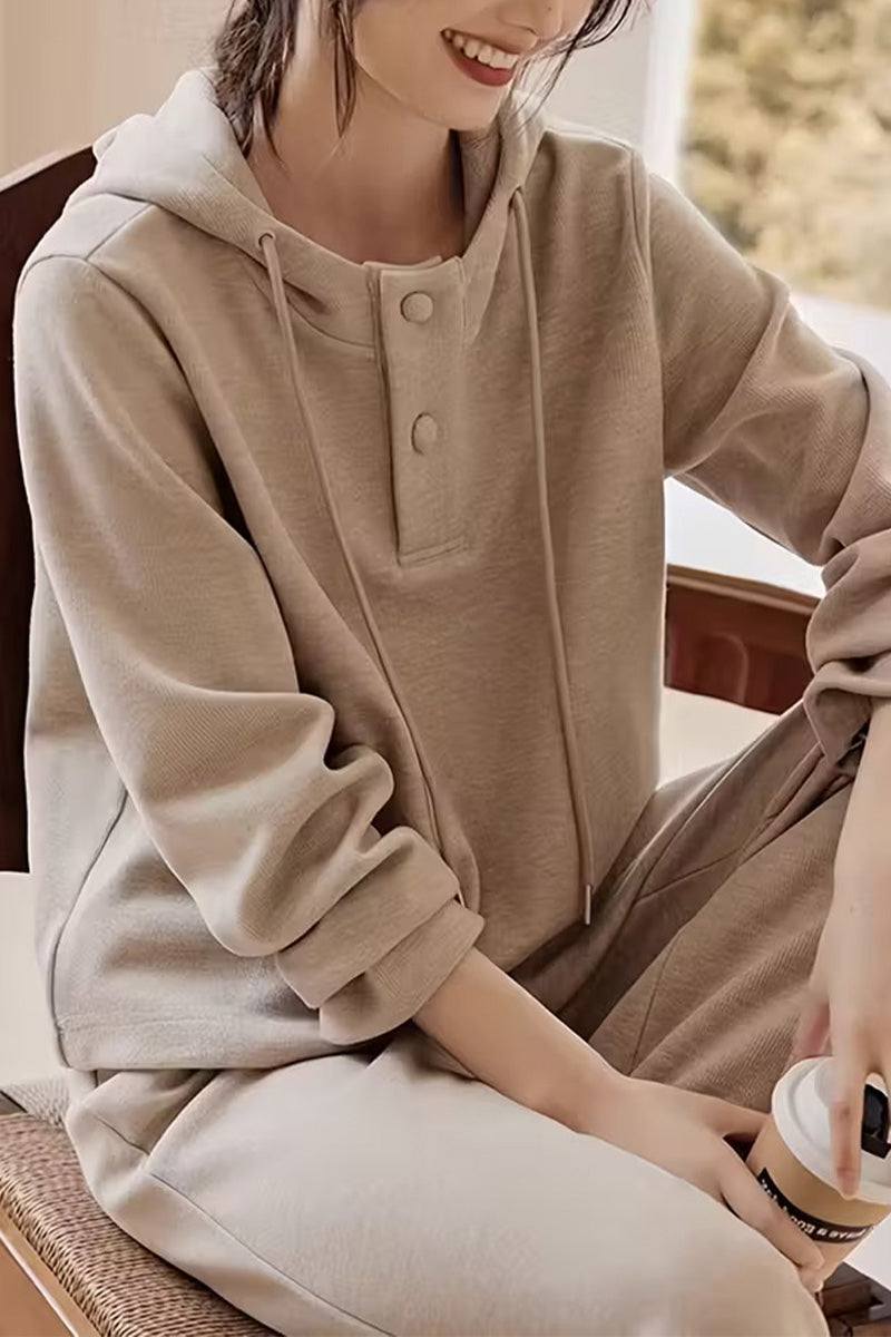 Woman wearing Quiet Comfort Everyday beige ribbed knit two-piece set with henley-style hoodie and wide-leg pants sitting indoors