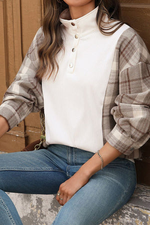 Waffle knit sweatshirt with plaid sleeves and button collar detail on woman sitting in jeans
