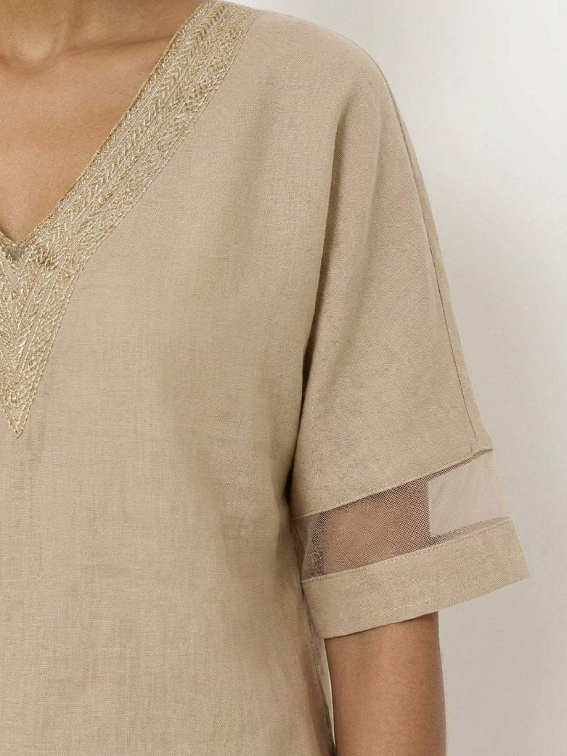 Mature woman wearing a lightweight linen top with V-neck and button detail in a relaxed boxy fit