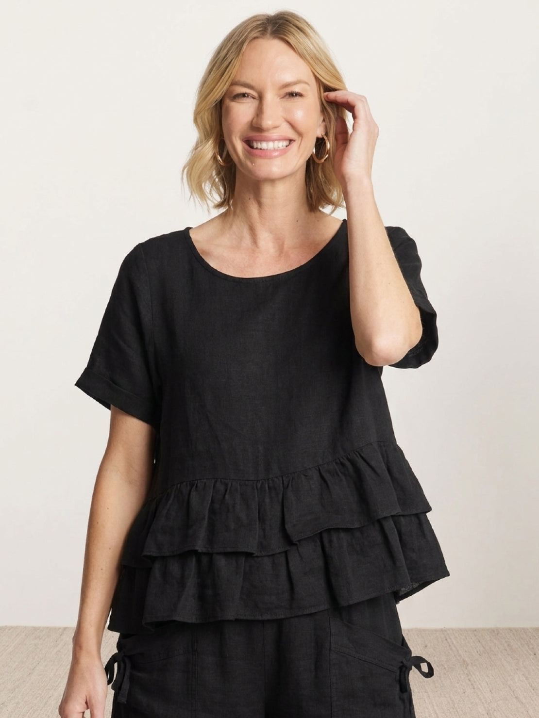 woman wearing navy blue cotton relaxed shorts and ruffle hem top two-piece co-ord set with side pockets and decorative ties