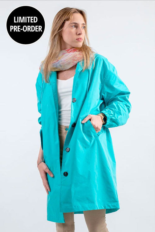 Woman wearing turquoise water resistant oversized windbreaker rain jacket with hood and button closure