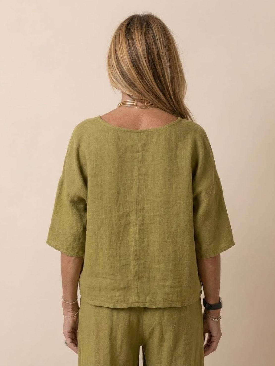 Back view of woman wearing olive green short-sleeved pullover and wide trouser matching set.