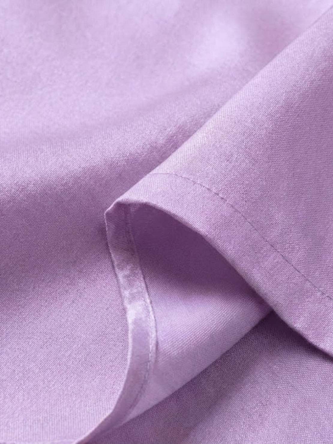 Close-up of silky soft lavender fabric from asymmetrical two-piece trouser set showing fine stitching detail