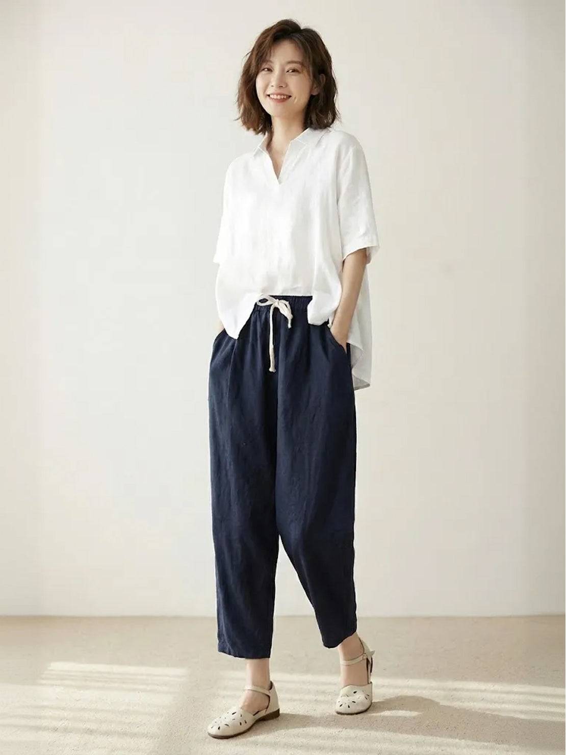 woman wearing orange relaxed fit straight pants standing on a street with hands in pockets