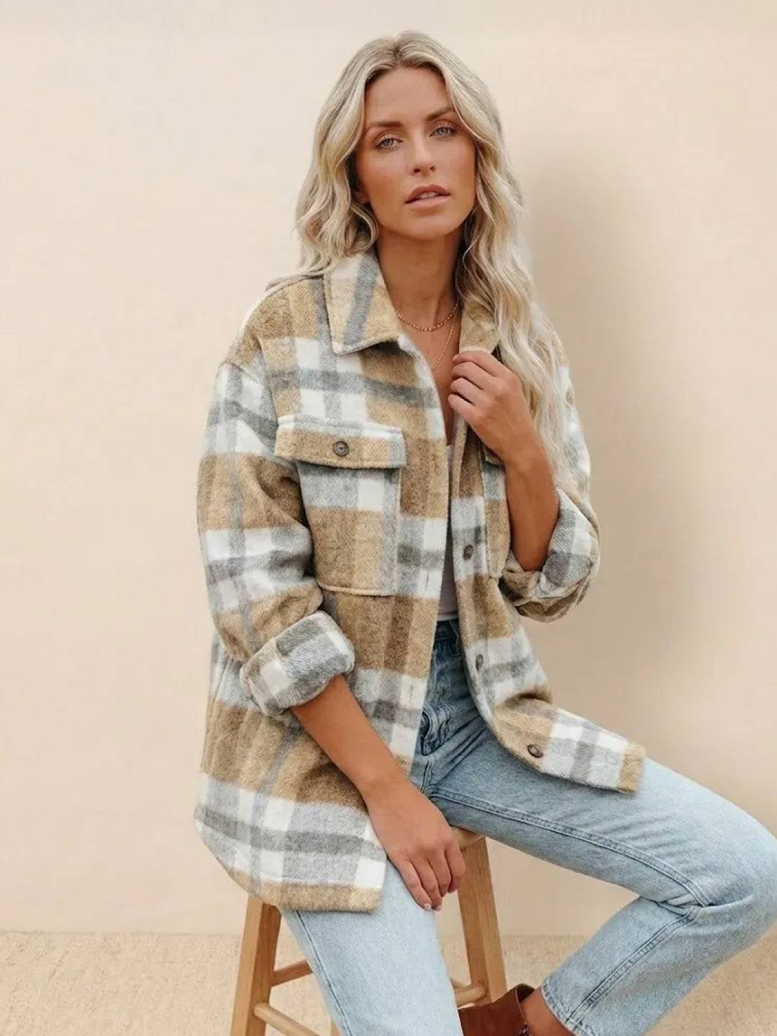 Woman wearing comfy flannel classic button-down shirt in beige and white plaid sitting on stool