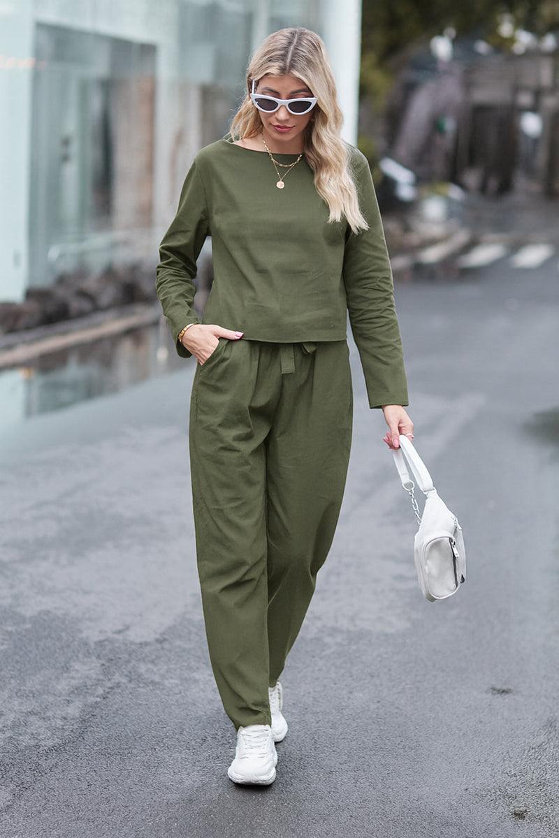 Woman wearing olive green cotton-linen monochrome longline top and wide-leg pants set walking outdoors with white sneakers and sunglasses