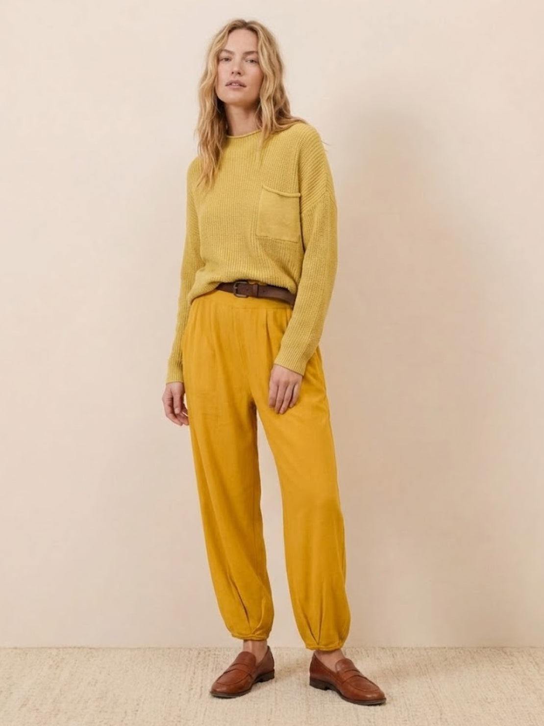 woman wearing yellow knit sweater and mustard relaxed trousers showcasing European minimalism style