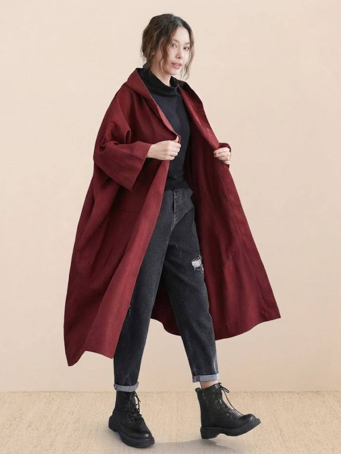 Woman wearing oversized maroon waterproof windbreaker jacket with hood and snap-button closure