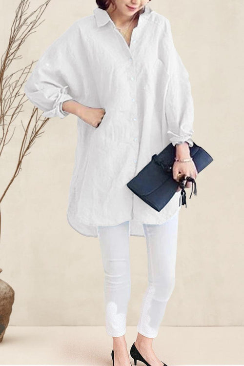 Woman wearing oversized white linen shirt with rolled-up sleeves and holding a black clutch bag