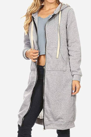 Woman wearing gray oversized long zip sweatshirt hoodie with front pockets and drawstring hood