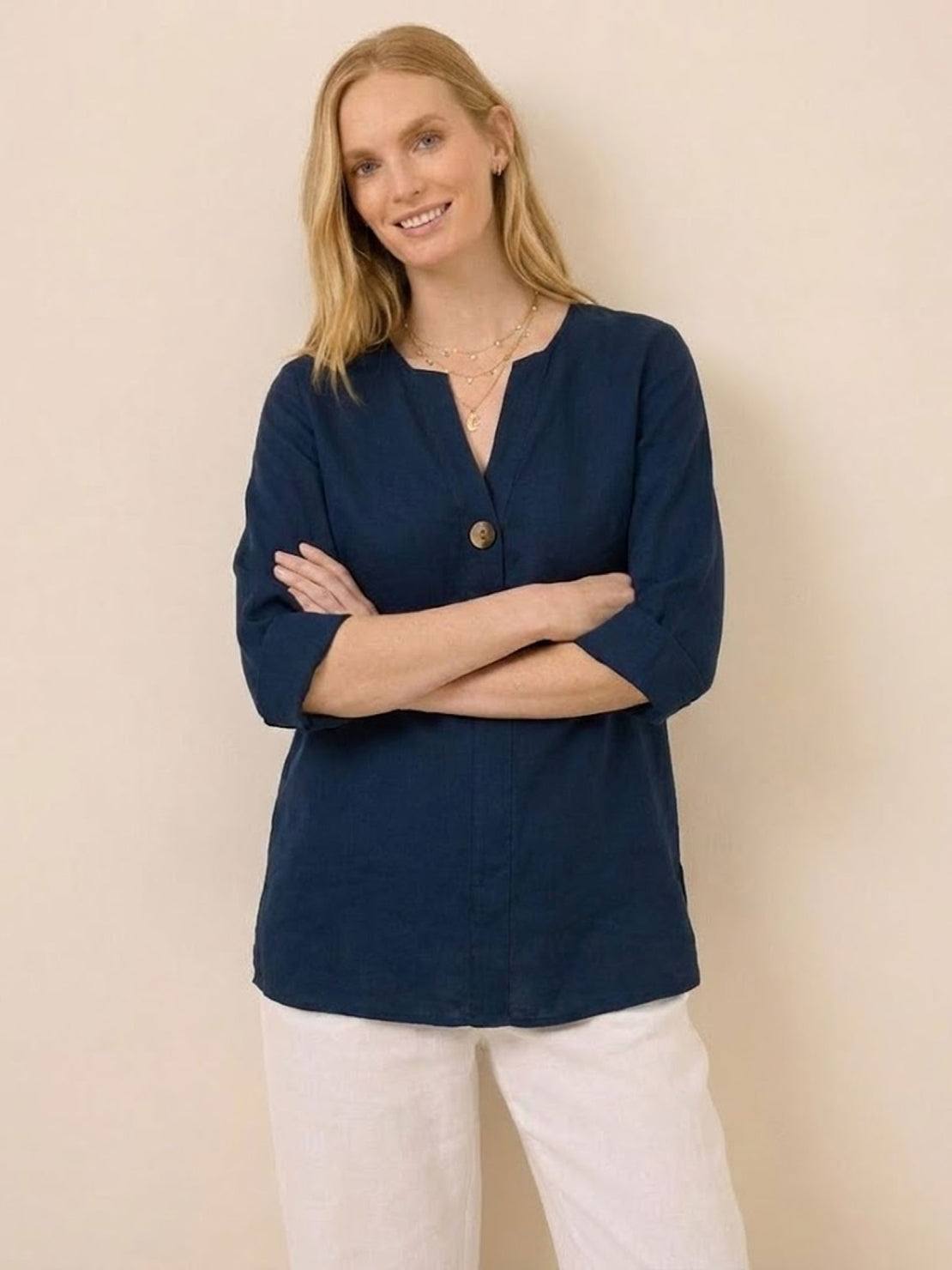 White pure linen age-defying shirt with button detail hanging on wooden hanger against white background