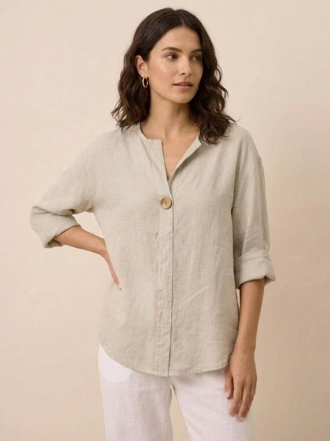 Woman wearing a beige pure linen age-defying shirt with button detail and rolled sleeves.