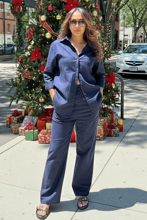 Woman wearing navy relaxed shirt and trousers two-piece set standing outdoors near Christmas decorations
