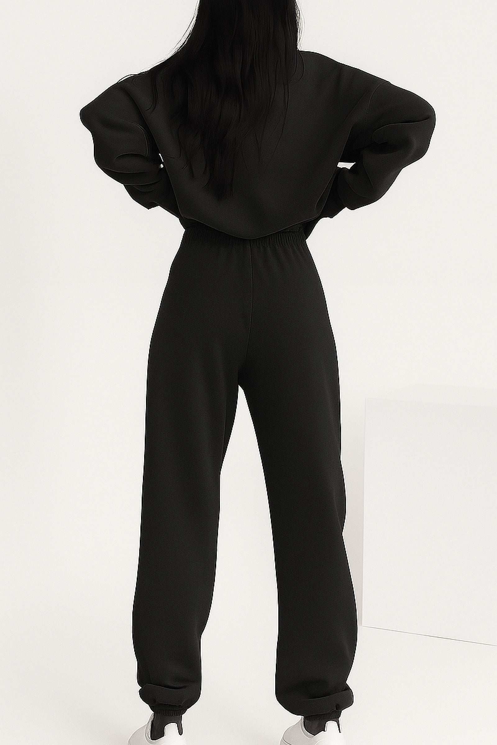 Back view of woman wearing black cotton blend tracksuit with stretch waistband and cuffs, showcasing relaxed fit and minimalist style.