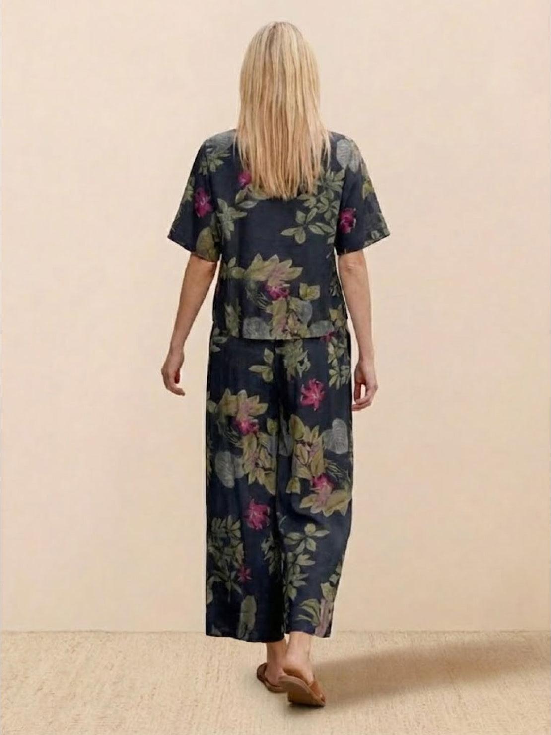 Woman wearing floral print loose fit co-ord set with wide-leg trousers and short sleeve top, back view