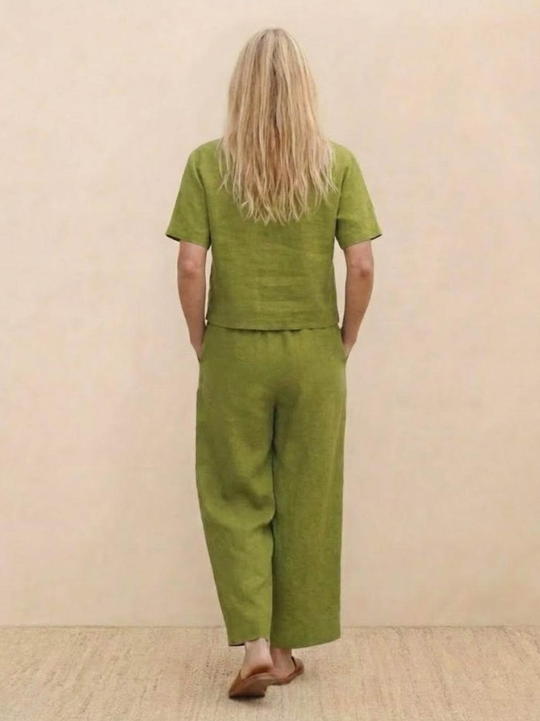 Back view of woman wearing green loose fit co-ord set with short sleeves and wide-leg pants barefoot