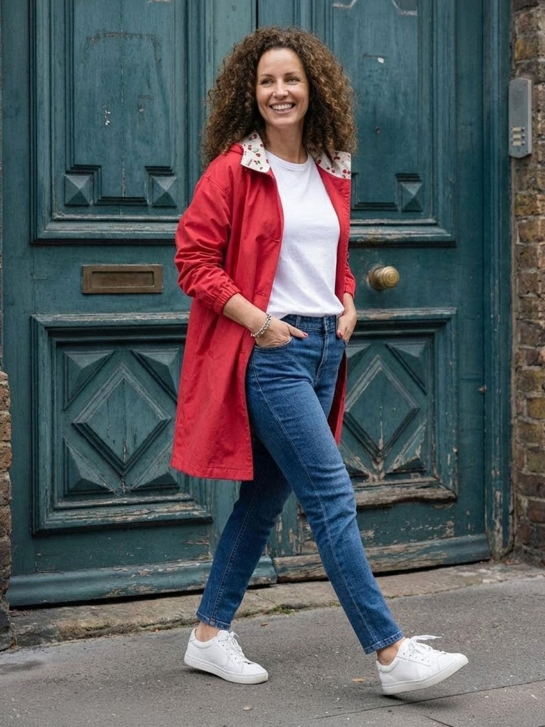 Woman wearing red Rain Couture Windbreaker with white t-shirt and blue jeans walking outdoors