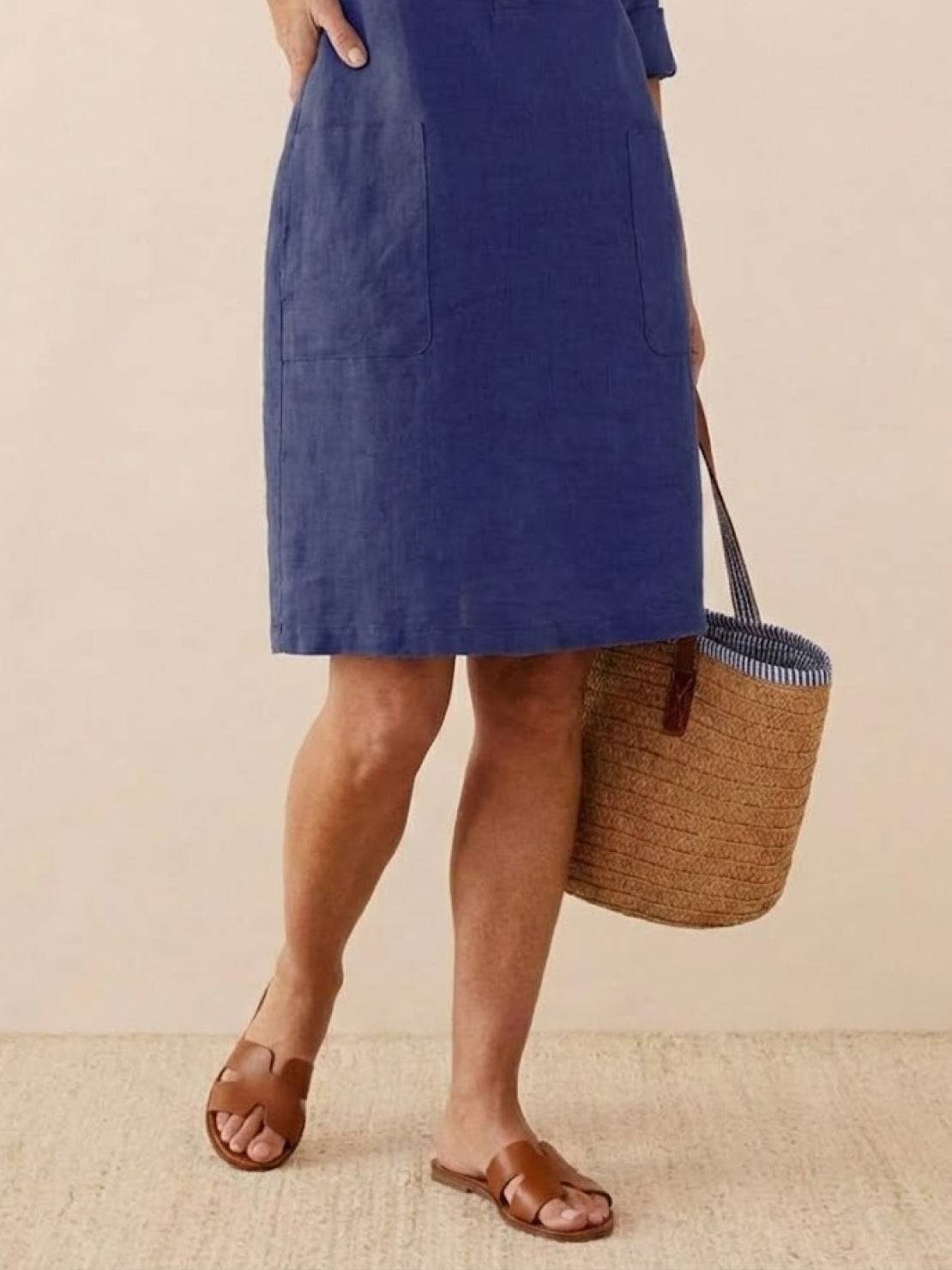 Blue knee-length cotton dress with pockets, 3/4 rolled sleeves, and casual fit paired with brown sandals and a woven basket bag.