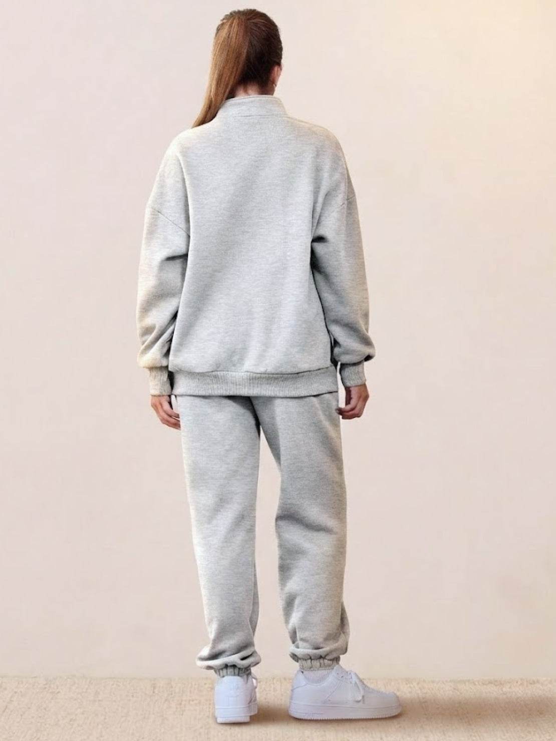 Back view of a woman wearing an ultra-soft and comfy grey co-ord tracksuit set with jogger pants and a zip-up jacket.