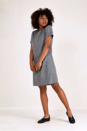 Woman wearing grey short sleeve shift dress with round neck and side pockets, knee-length professional style