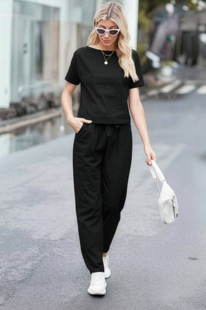Woman wearing black cotton linen set with short-sleeve top and straight-leg pants walking outdoors