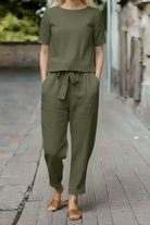 Woman wearing olive green cotton linen set with short-sleeve top and straight-leg pants outdoors