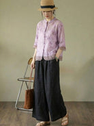Woman wearing 100% cotton linen Tuscany two-piece set with embroidered top and wide-leg trousers in a bright room