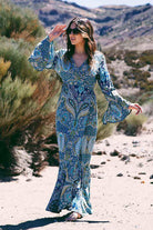 Woman wearing Desert Spell Bohemian Print ruffle maxi dress with bell sleeves and waist tie in a desert setting